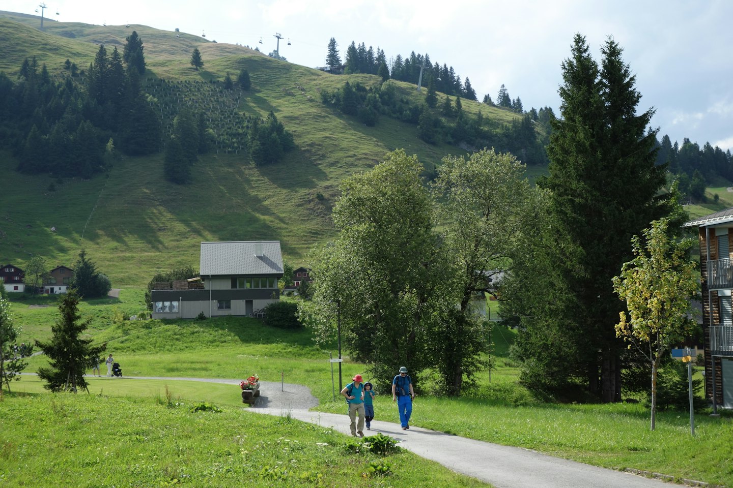 Famiglia di tre persone che cammina lungo un sentiero lastricato in montagna.